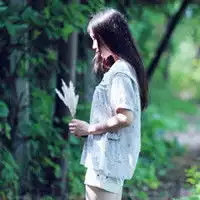 求唯美的女头像,背景为绿色树林,侧身,手里拿花,长发