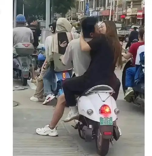 这对男女也太激情了,骑着电动车还不停接吻,就不怕发生车祸吗