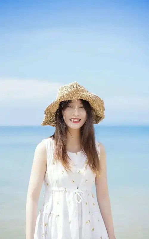 海边草帽少女,在阳光下看起来清新白皙可人,白色碎花裙更显青春活力