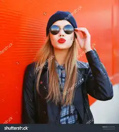 时尚的红色唇膏金发女孩的画像戴着黑色的摇滚风格在户外玩